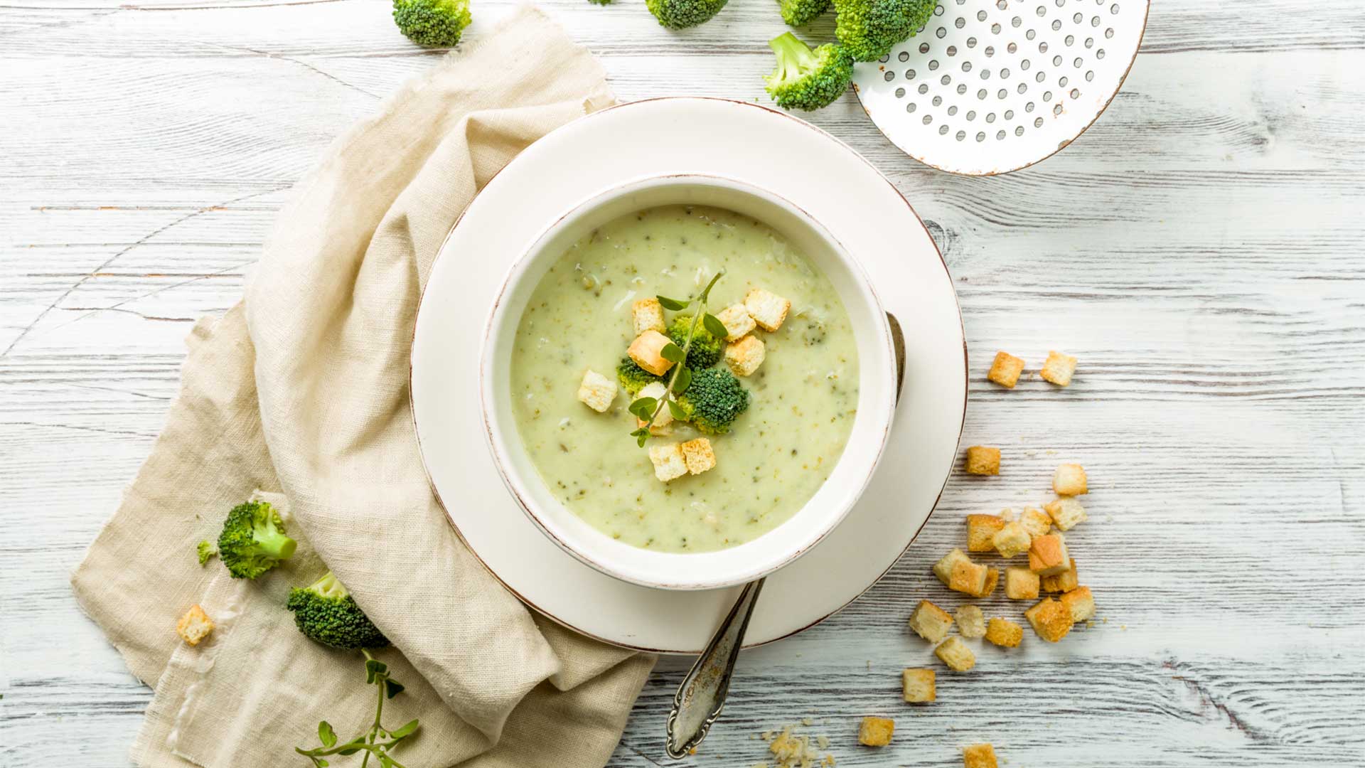 fresh broccoli soup with croutons and herbs in a bowl