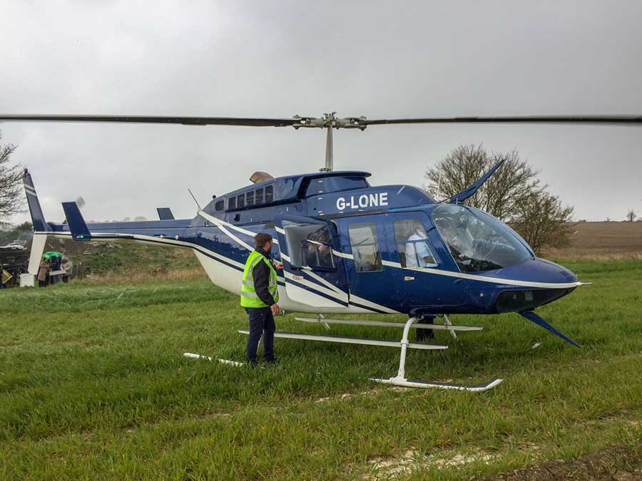 Passengers in hi-vis jackets getting off a dark blue helicopter