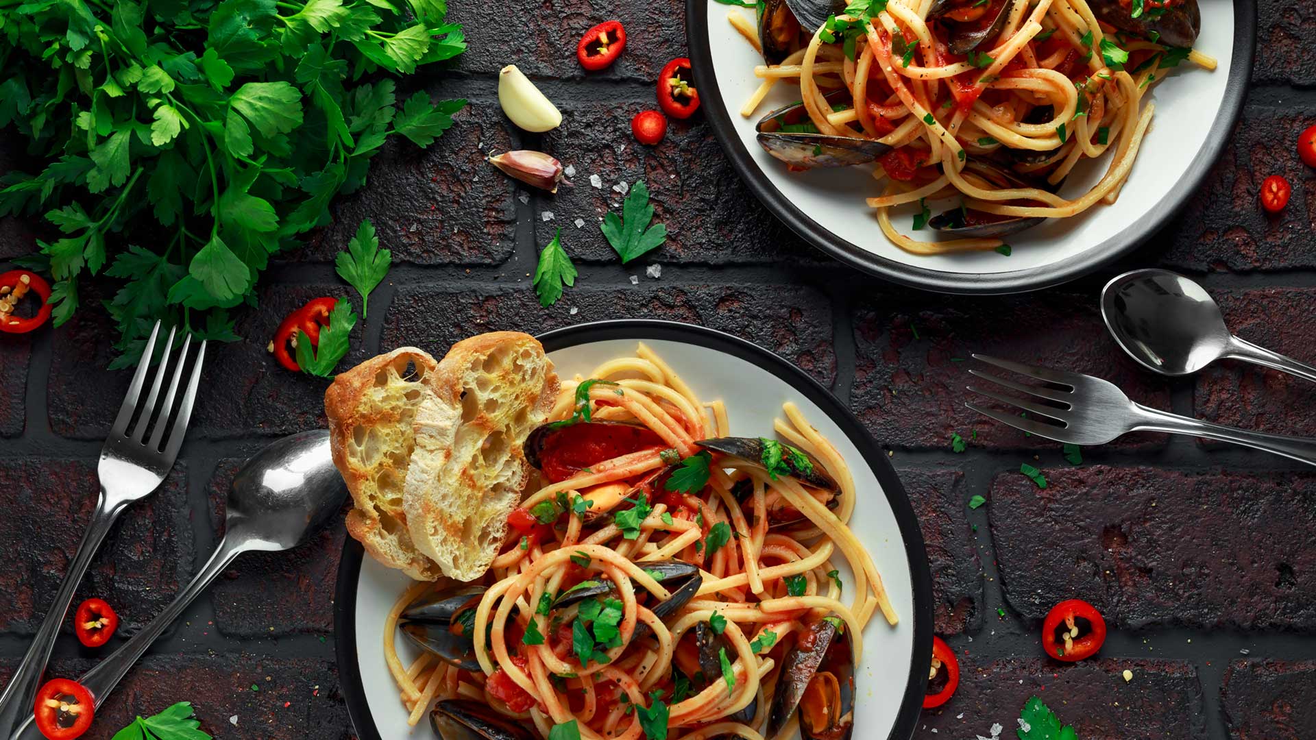 Mussel pasta linguine on a white plate with coriander and chillis