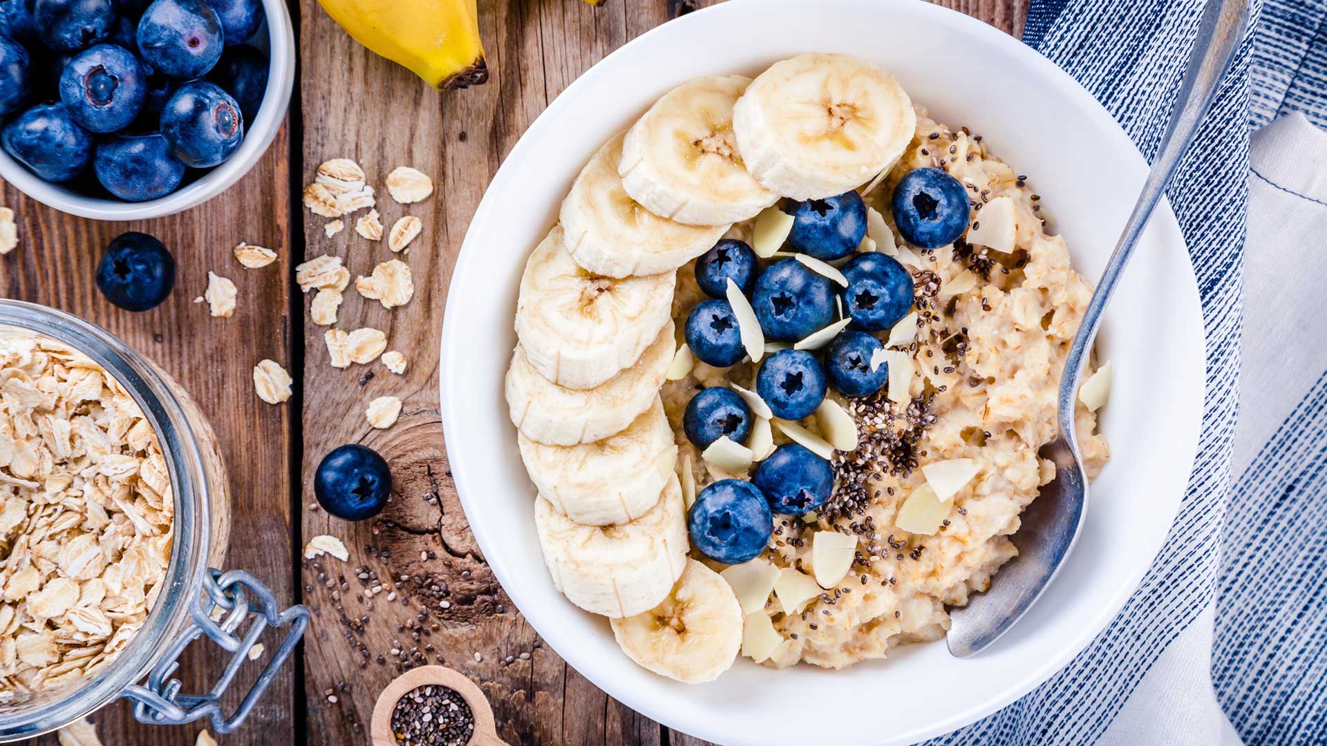 Breakfast: oatmeal with bananas, blueberries, chia seeds and almonds on a plate on wooden table