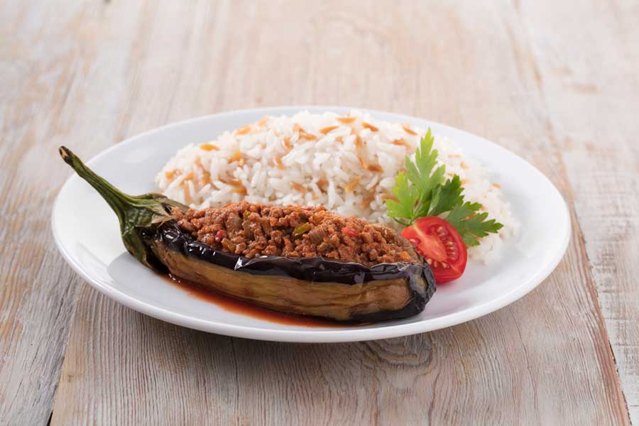 Stuffed Aubergine, Eggplant with rice on a white plate on wooden background 