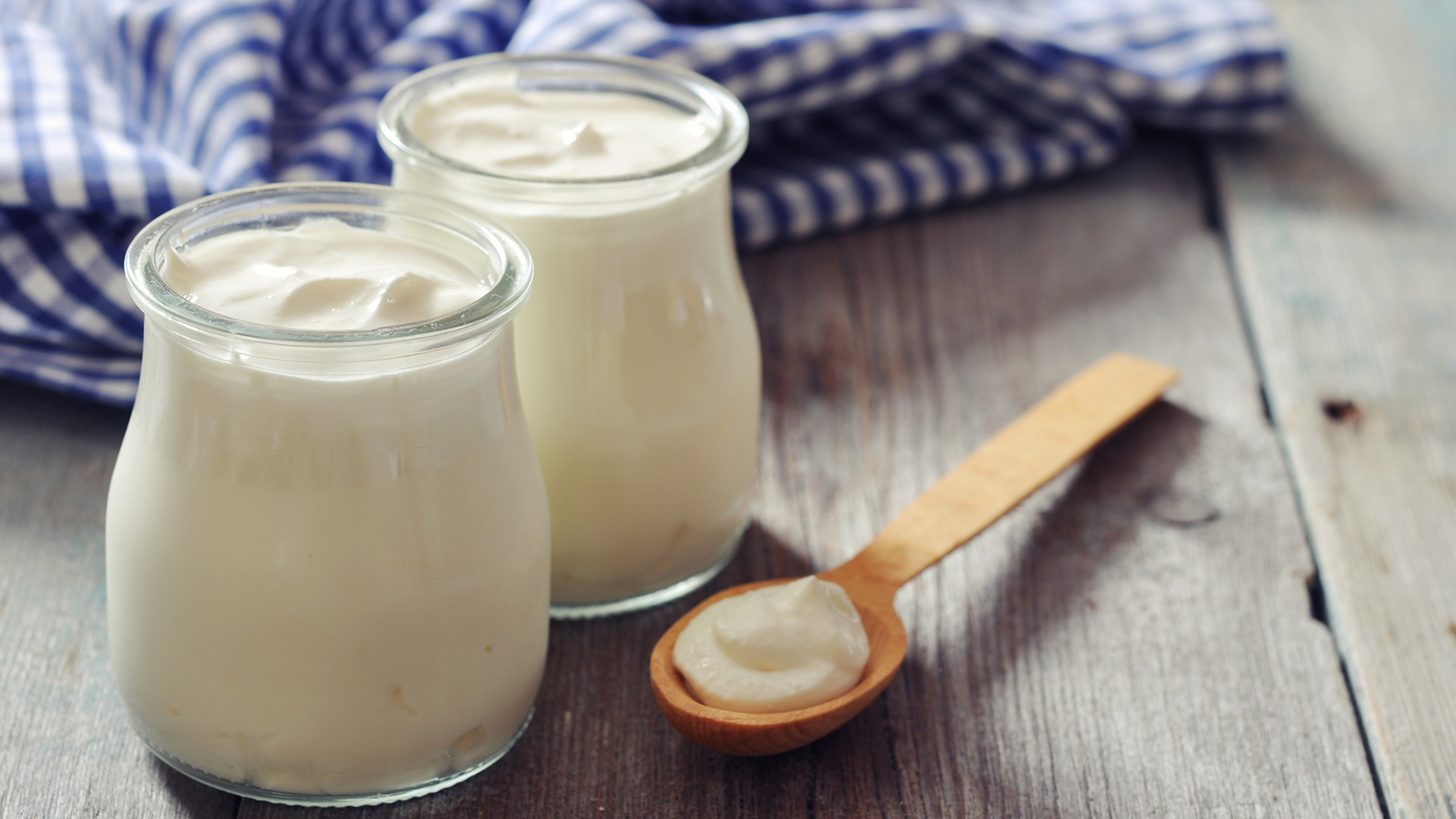 Turkish yogurt in a glass jars with spoons on wooden background