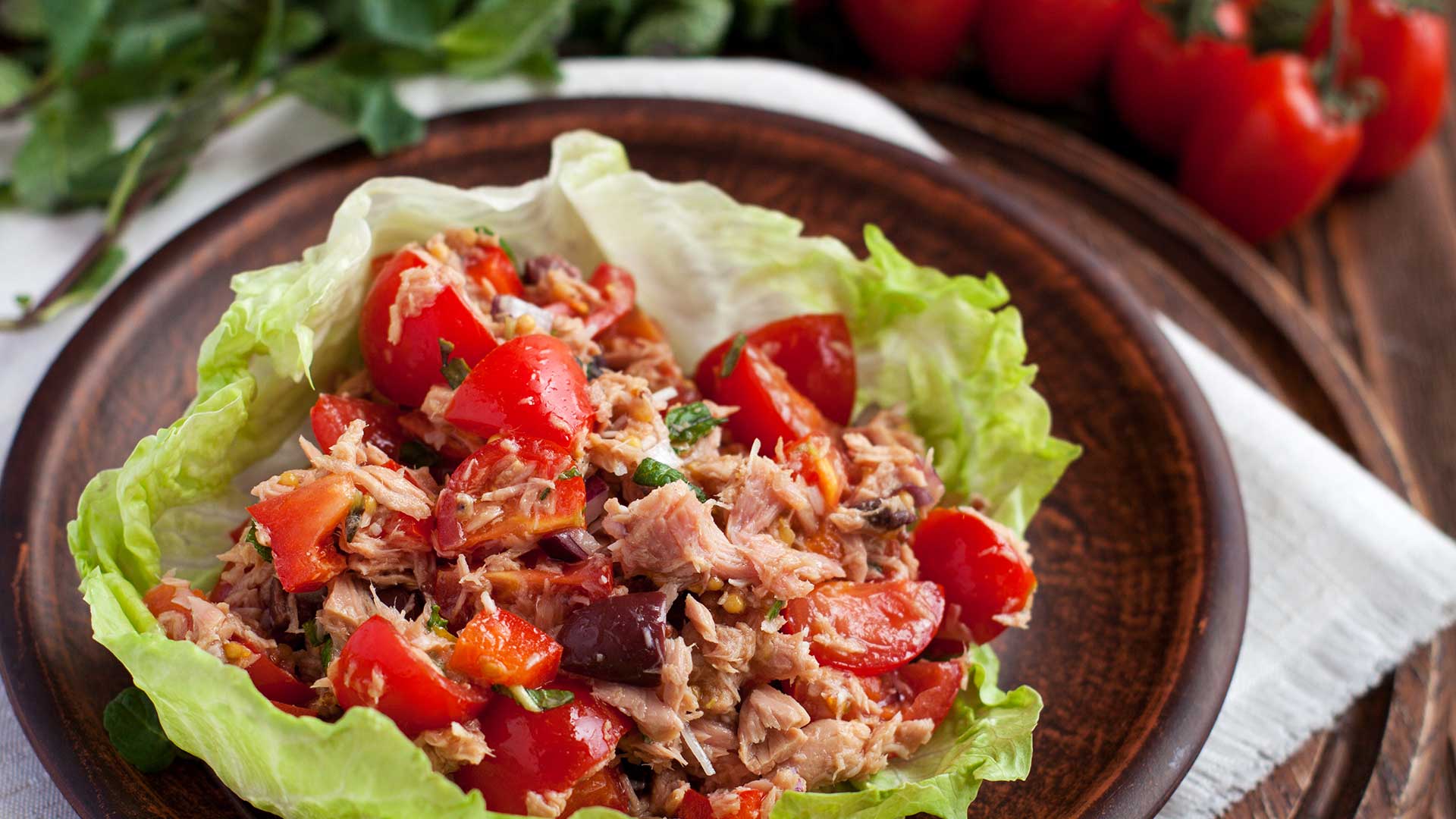 Healthy appetisers lettuce wraps with canned tuna, bell pepper, herbs on clay plate