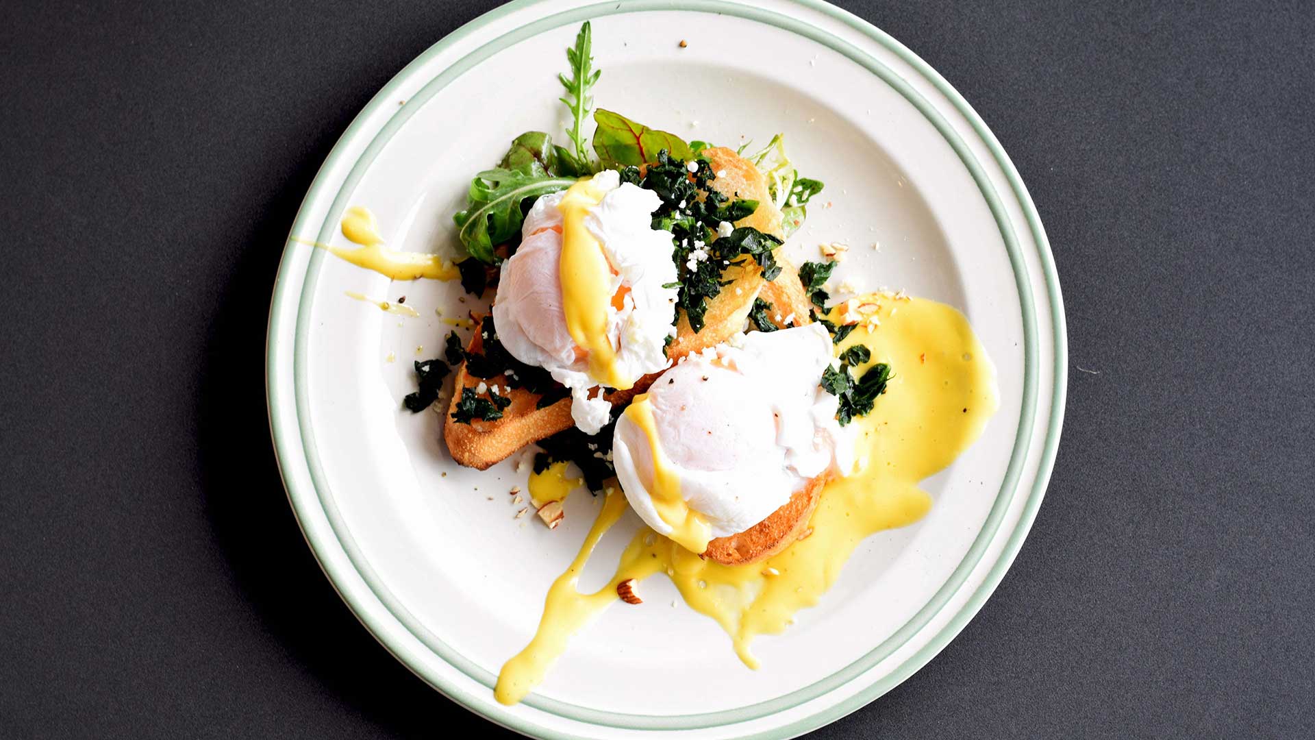 eggs benedict on white plate with black background