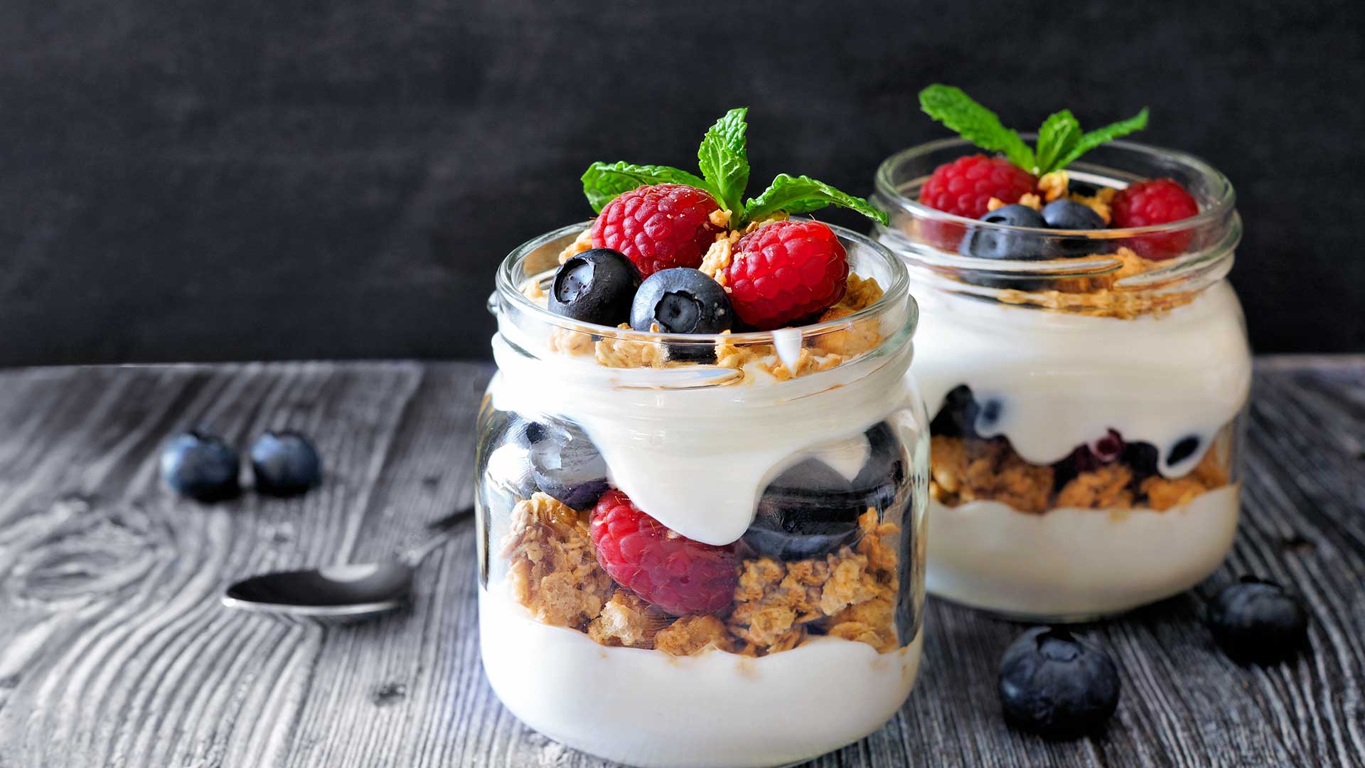 Fruit and yogurt parfait in a jar on black wooden table