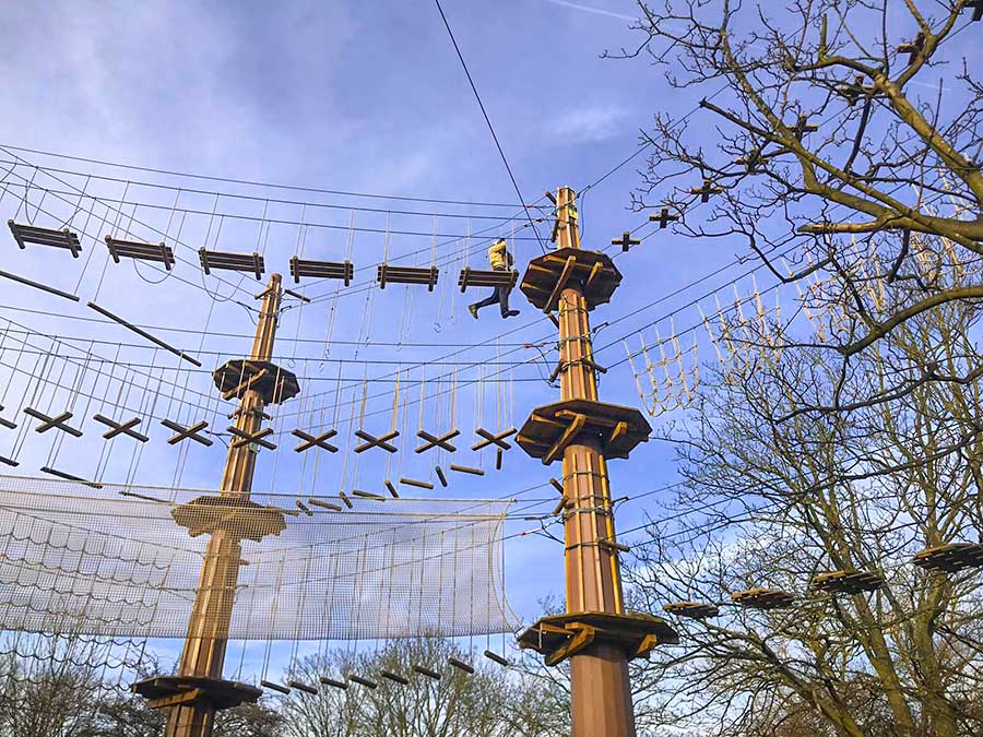 Rope bridges and safety nets between high pillars against a blue sky background