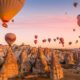 Hot air balloons filled with tourists during a pink sunrise floating along valleys of Göreme National Park