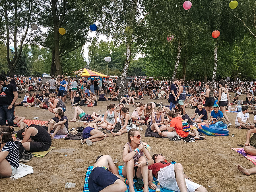 Festival goers sitting on dry grass at Sziget Festival