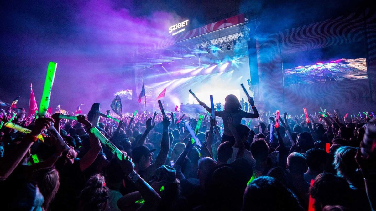 A crowd dancing to music at Sziget main stage with bright fluorescent lights