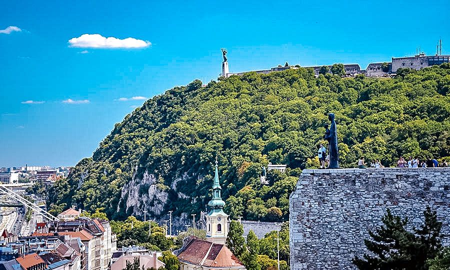 The Statue of Liberty on top of a high hill overlooking the city of Budapest