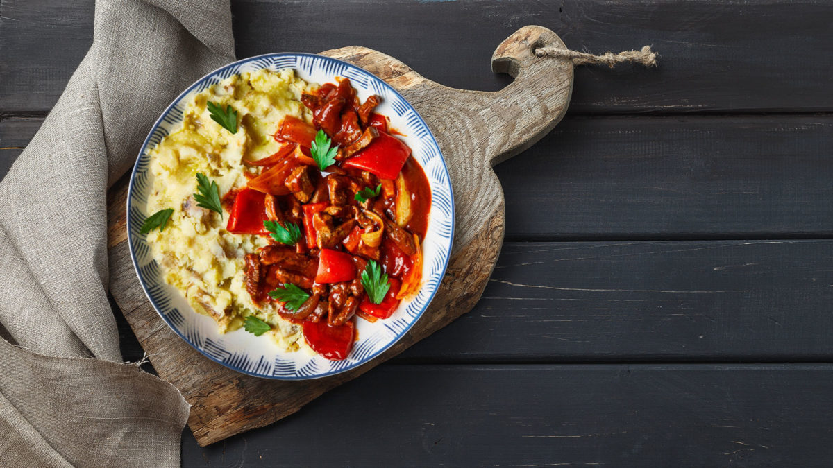 beef goulash with mash on plate on black table