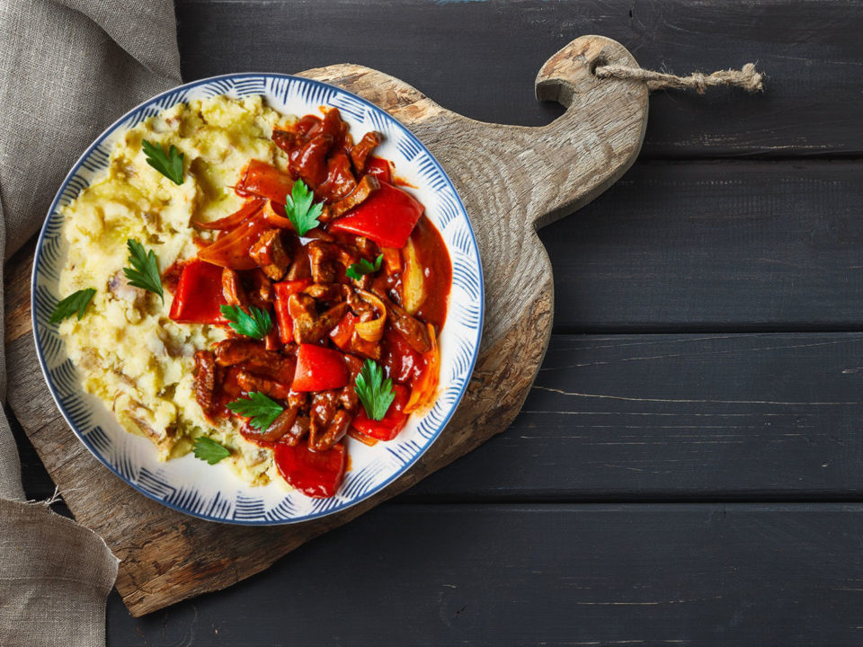 beef goulash with mash on plate on black table