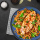 fish with noodles in blue plate on black table