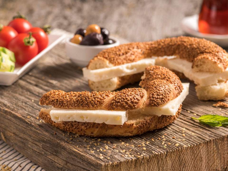 Close up of traditional Turkish simit bagel with cheese, tomatoes, olives, cucumber and tea