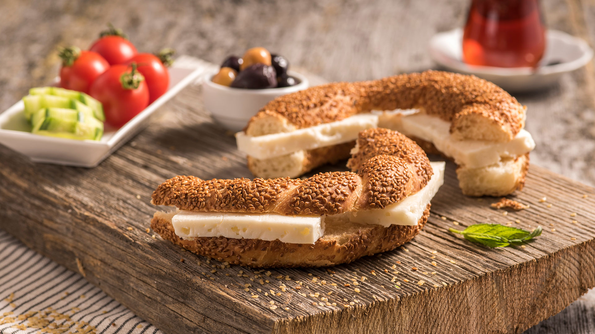 Close up of traditional Turkish simit bagel with cheese, tomatoes, olives, cucumber and tea